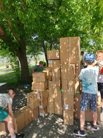 uczniowie w cieniu drzewa budują konstrukcję z kartonów