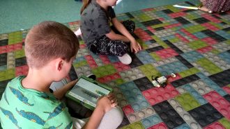 chłopcy na dywanie tablet sterowanie robotem